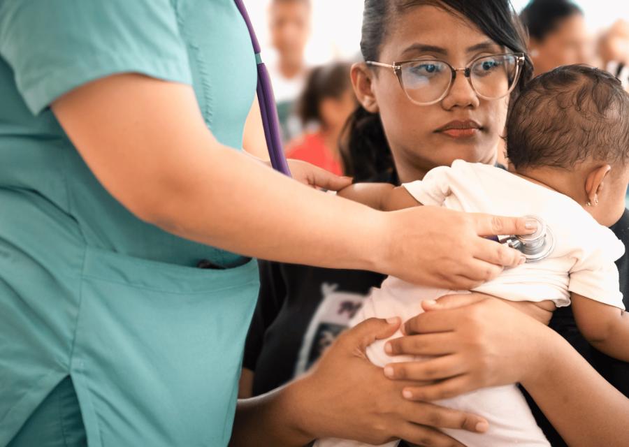 Donna con sua figlia neonata in braccio durante una visita medica
