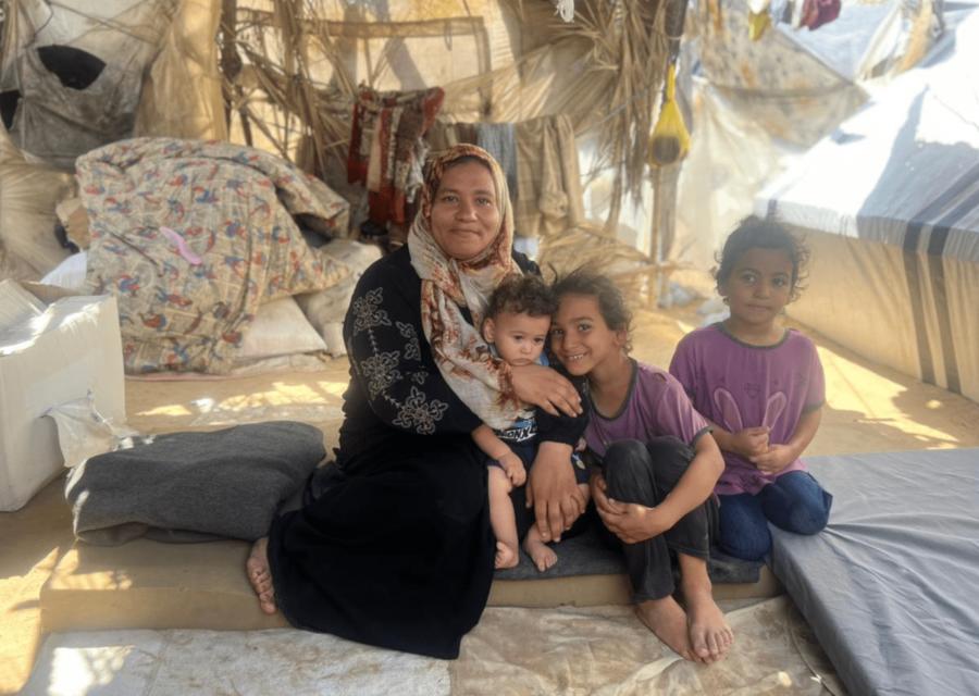 Madre con bambini sorridenti in una tenda a Gaza