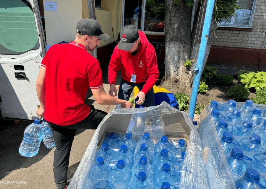 operatori Save the Children che distribuiscono bottiglie di plastica da un camion