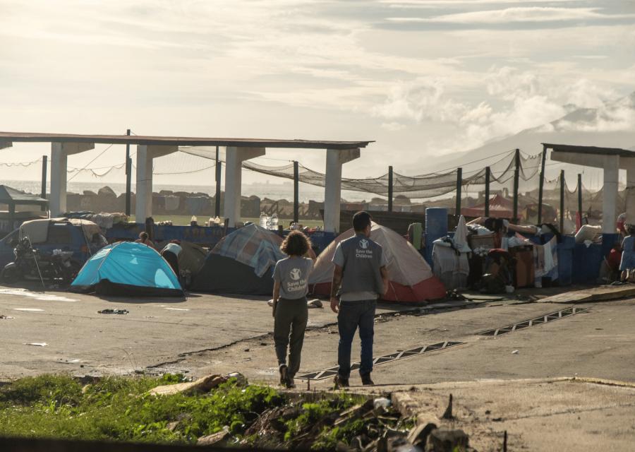 Due operatori di Save the Children di fronte a un campo con tende dove stanno vivendo sopravvissuti al terremoto.