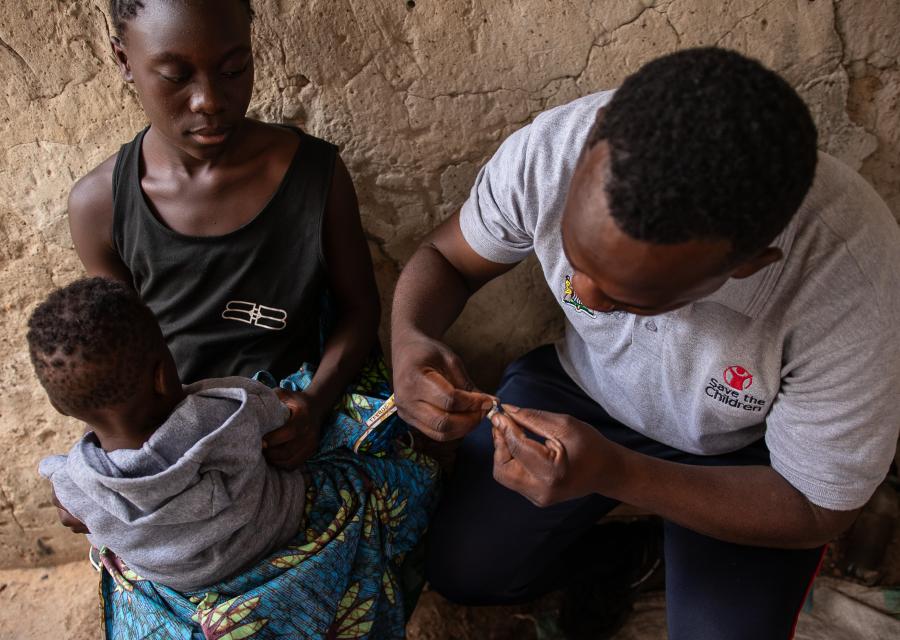 Bambino in braccio ad una donna viene vaccinato da operatore Save the Children
