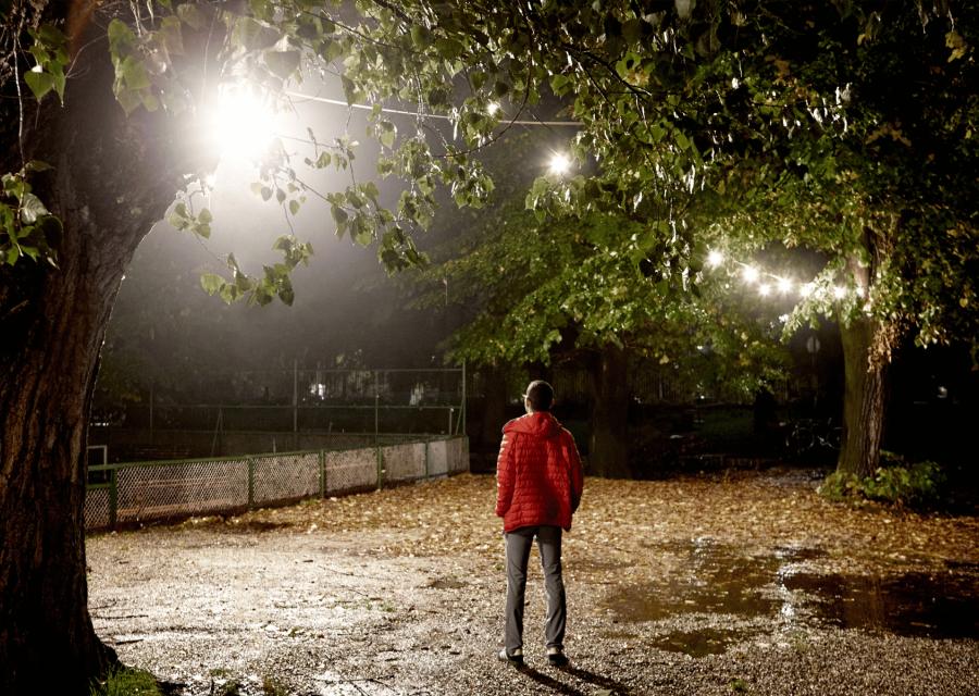 Ragazzo di spalle al centro di un giardino di notte