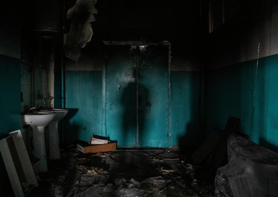 Ombra di una persona sul muro in una stanza buia distrutta