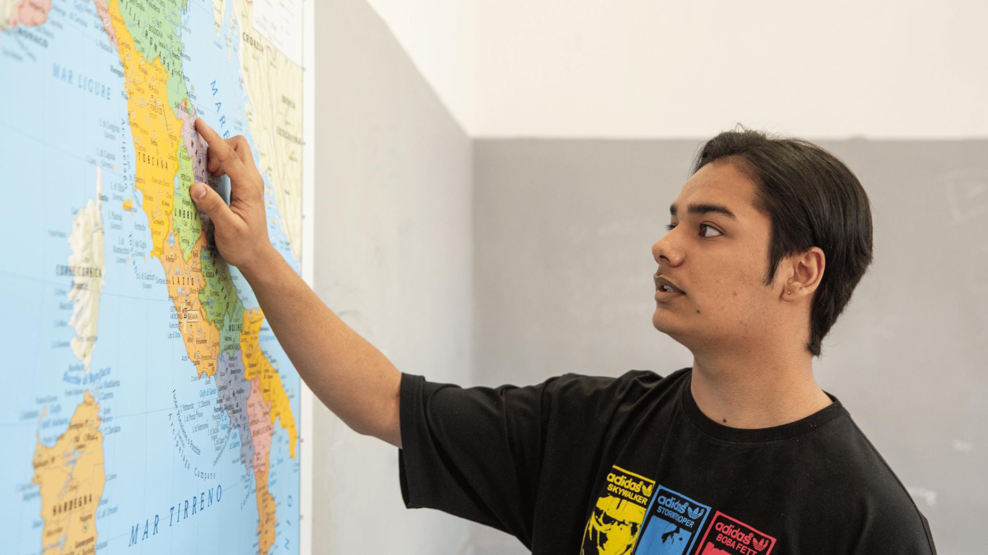 Ragazzo con background migratorio che indica l'Italia sulla cartina