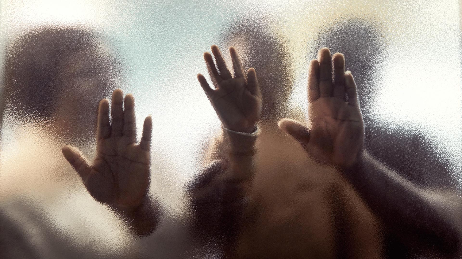 3 sagome di mani contro un vetro sfocato