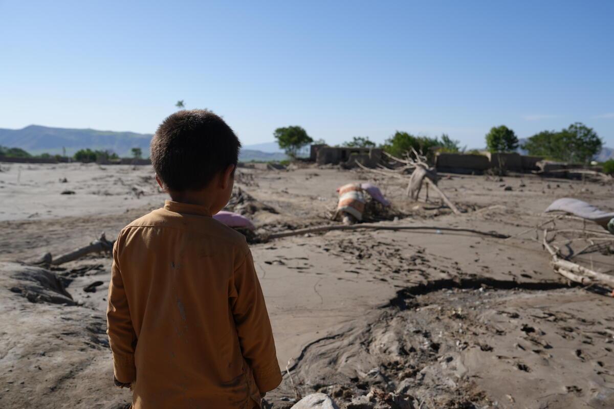 Foto di un bimbo di spalle mentre guarda la desolazione dovuta alle eccessive piogge.