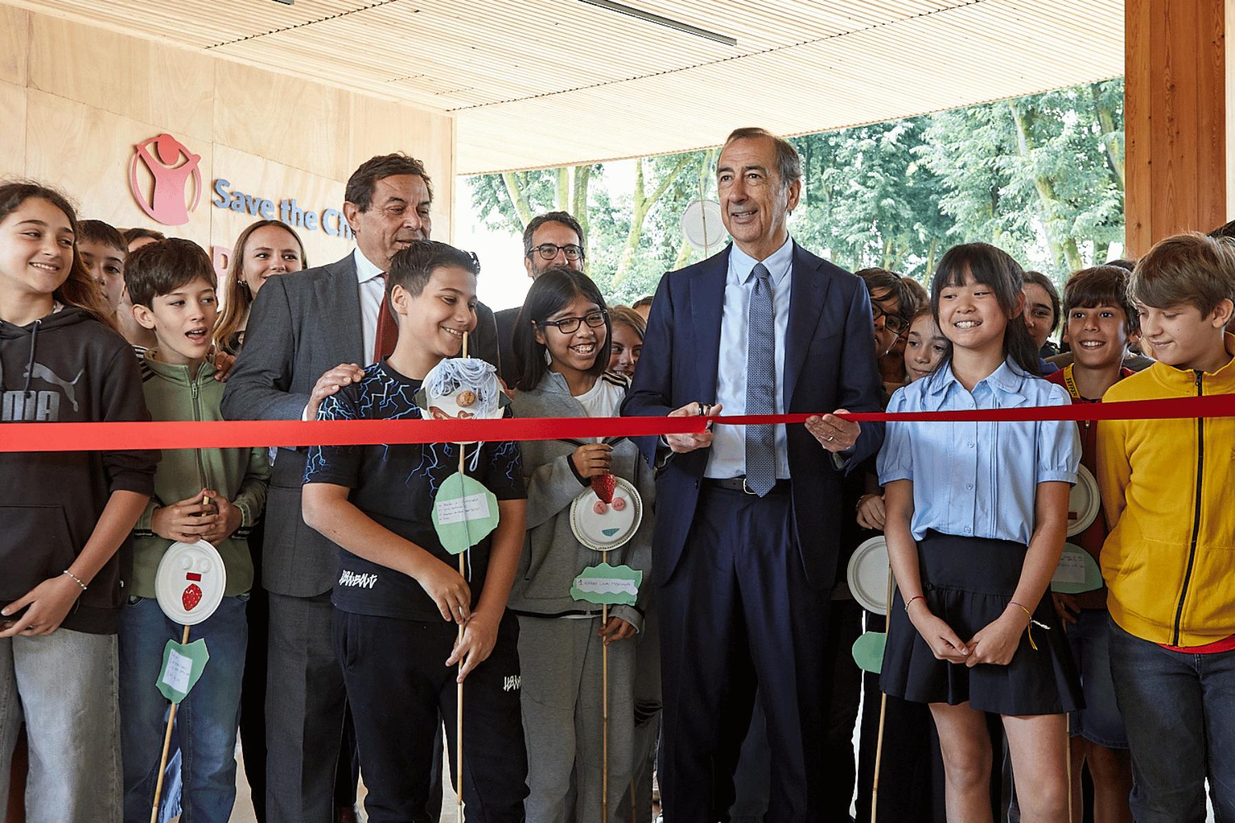 Taglio del nastro rosso per l'inaugurazione con il sindaco di Milano, Giuseppe Sala, al centro e bambini e bambine intorno.