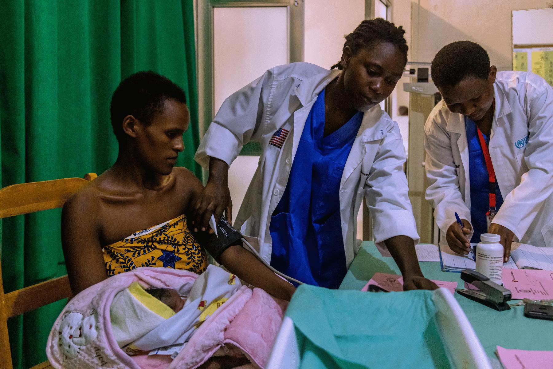 Operatrici sanitarie di Save the Children che misurano la pressione al braccio ad una donna