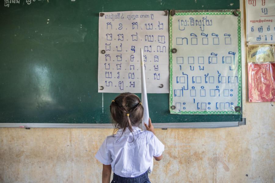 bambina del Vietnam che guarda alcuni cartelli appesi ad una lavagna scolatisca