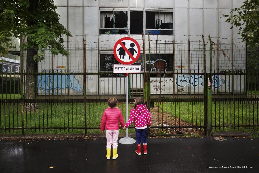 due bambine si tengono per mano davanti a un cartello con un divieto con scritto "vietato ai minori"