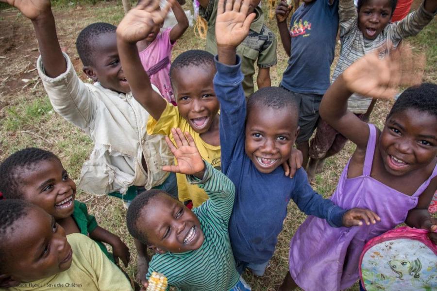 gruppo di bambini sorridenti con le mani alzate vestiti con diversi colori, foto dall'alto