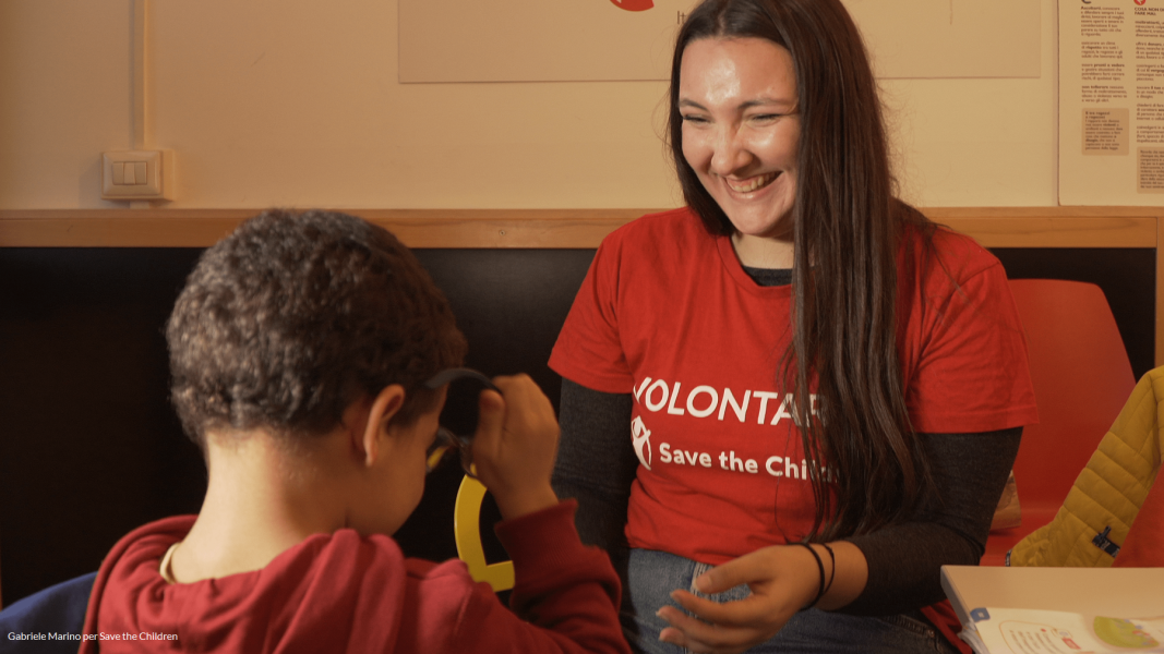 volontaria de servizio civile con save the children mentre gioca sorridente con un bambino