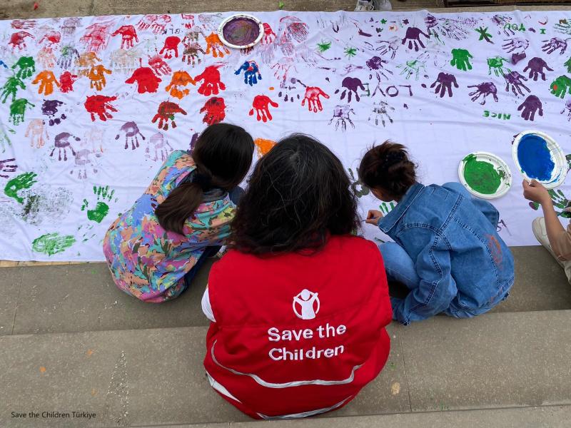 Operatrice Save the Children con due bambini che dipingono con le mani 