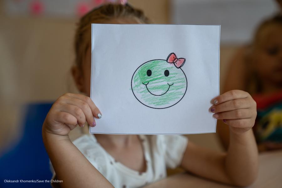bambina che tiene un foglio davanti al viso con smile