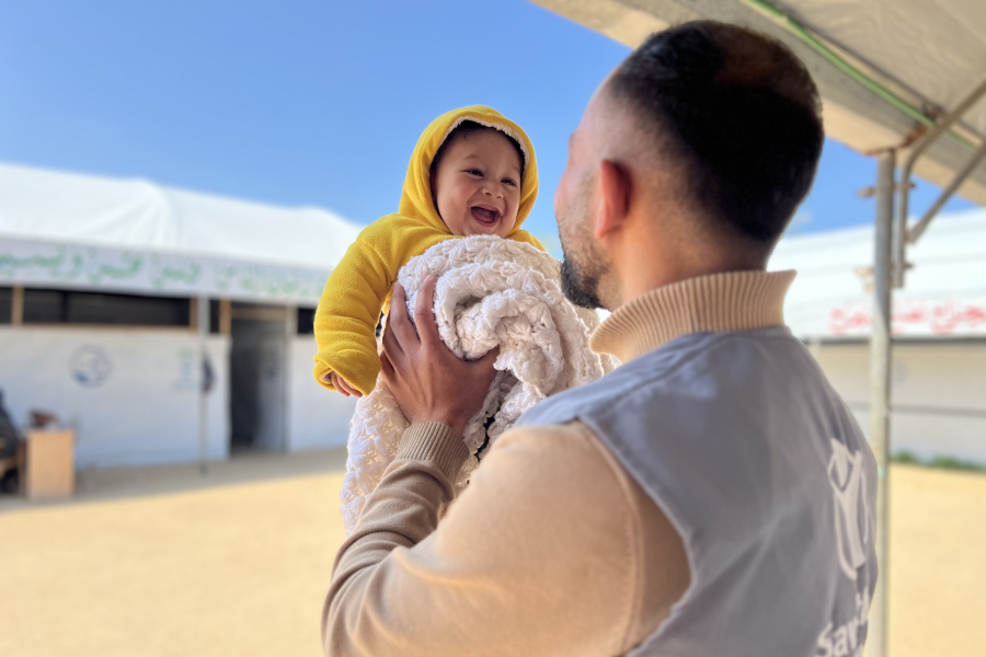 Bambina sorridente in braccio ad operatore Save the Children
