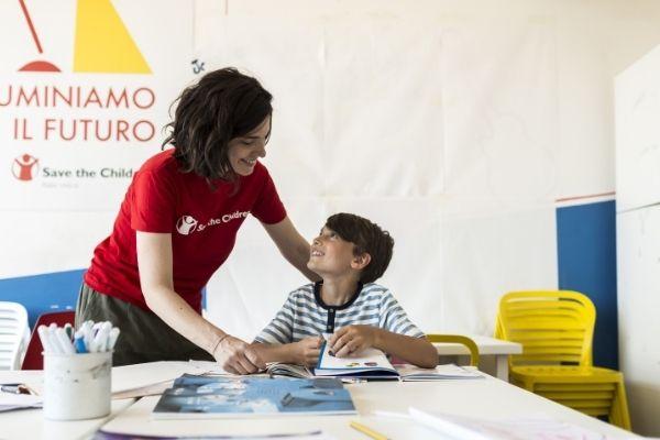 un'educatrice del Punto Luce di Save the Children aiuta un bambino a fare i compiti